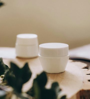 A clean and simple display of skincare containers on a natural wooden board.